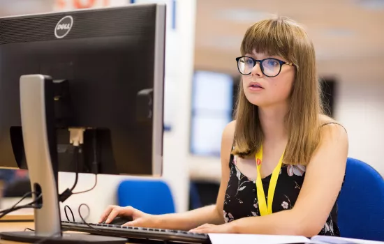 A female student sits working on a computer.