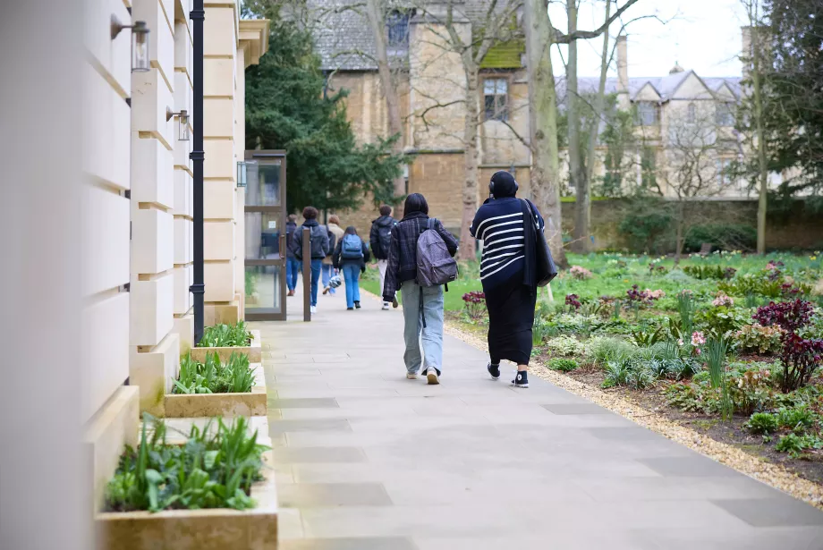 Two female students walk out of the Levine building at Trinity; their backs are to the photographer.