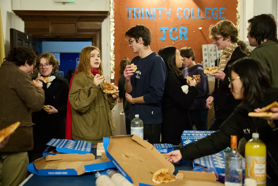 A group of students mingle during a pizza night in the Trinity JCR. 